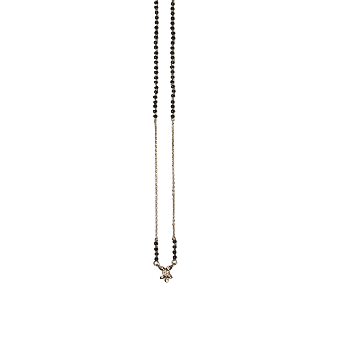 A delicate beaded necklace with small black beads on a fine silver chain, laid flat on a light beige background.