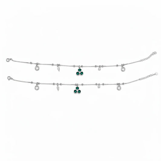 Shyni Jewelry silver charm anklet featuring a green clover pendant, small clear crystals, and delicate metal charms.