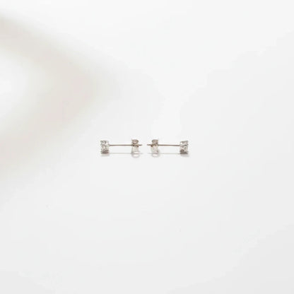 Shyni Jewelry square-shaped stud earrings in silver with clear sparkling stones on a minimalist white background