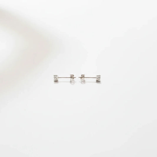 Shyni Jewelry square-shaped stud earrings in silver with clear sparkling stones on a minimalist white background
